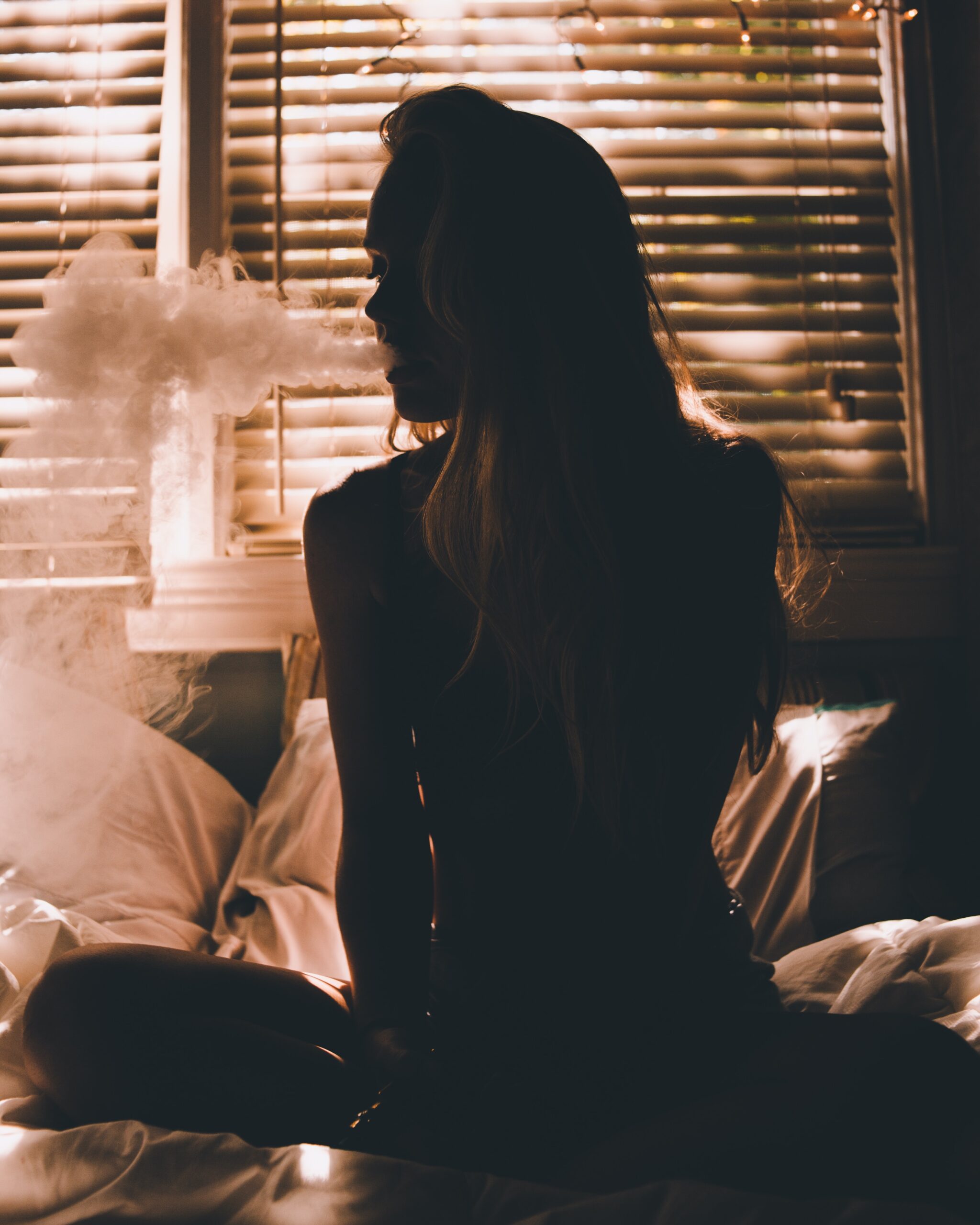 Fata care stă în pat în poziție yoga și fumează