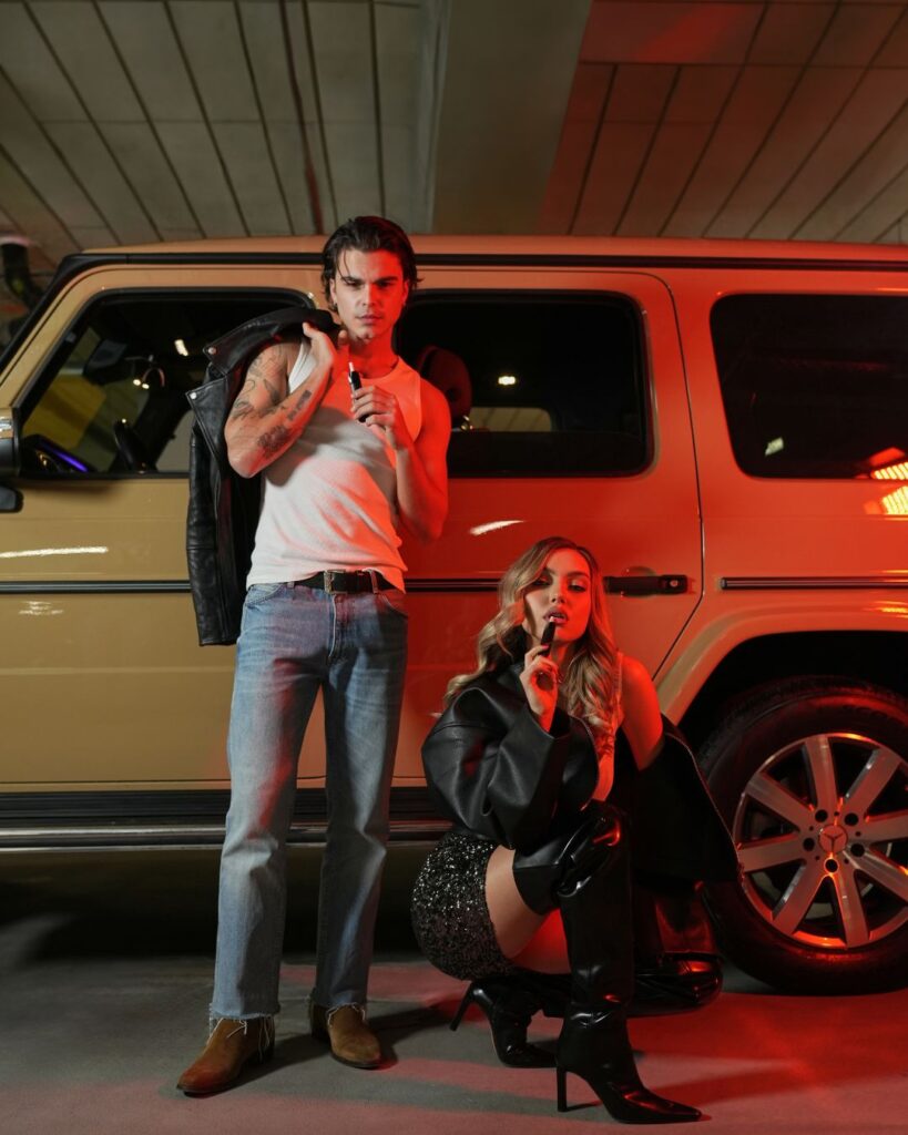 Model masculin și model feminim vapează Yoop Filtro în parcare lângă o mașină 