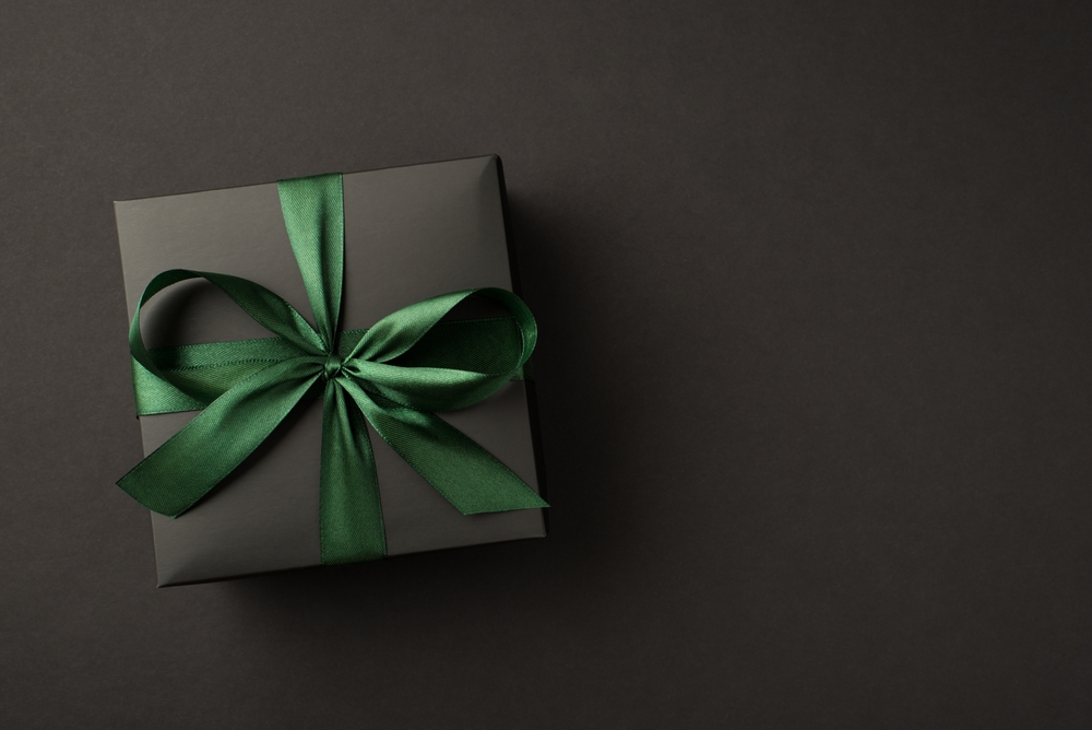 Background negru cu un cadou de asemenea negru impachetat frumos cu funda verde