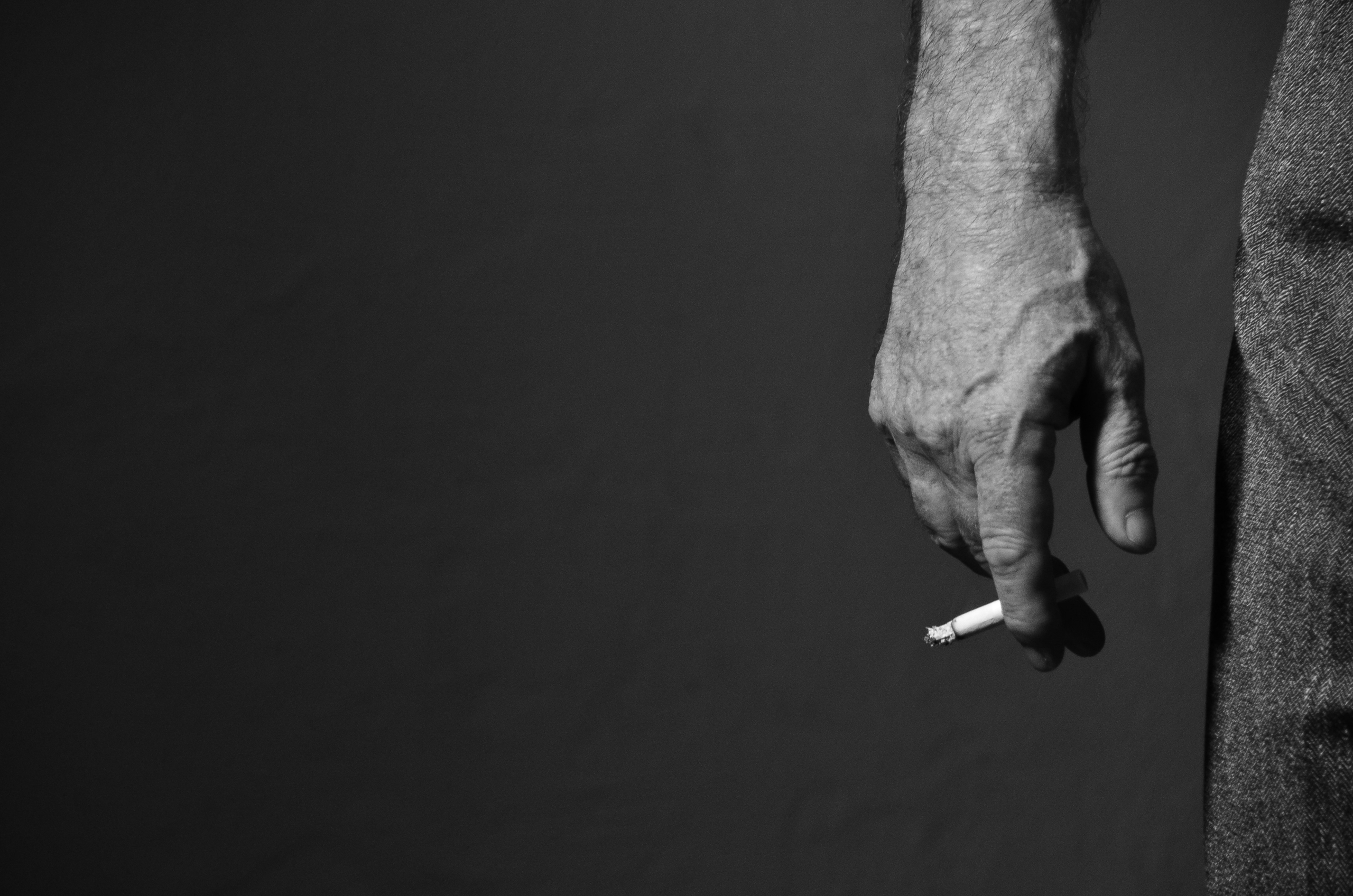 mana unui barbat cu tigara aprinsa pe fundal negru