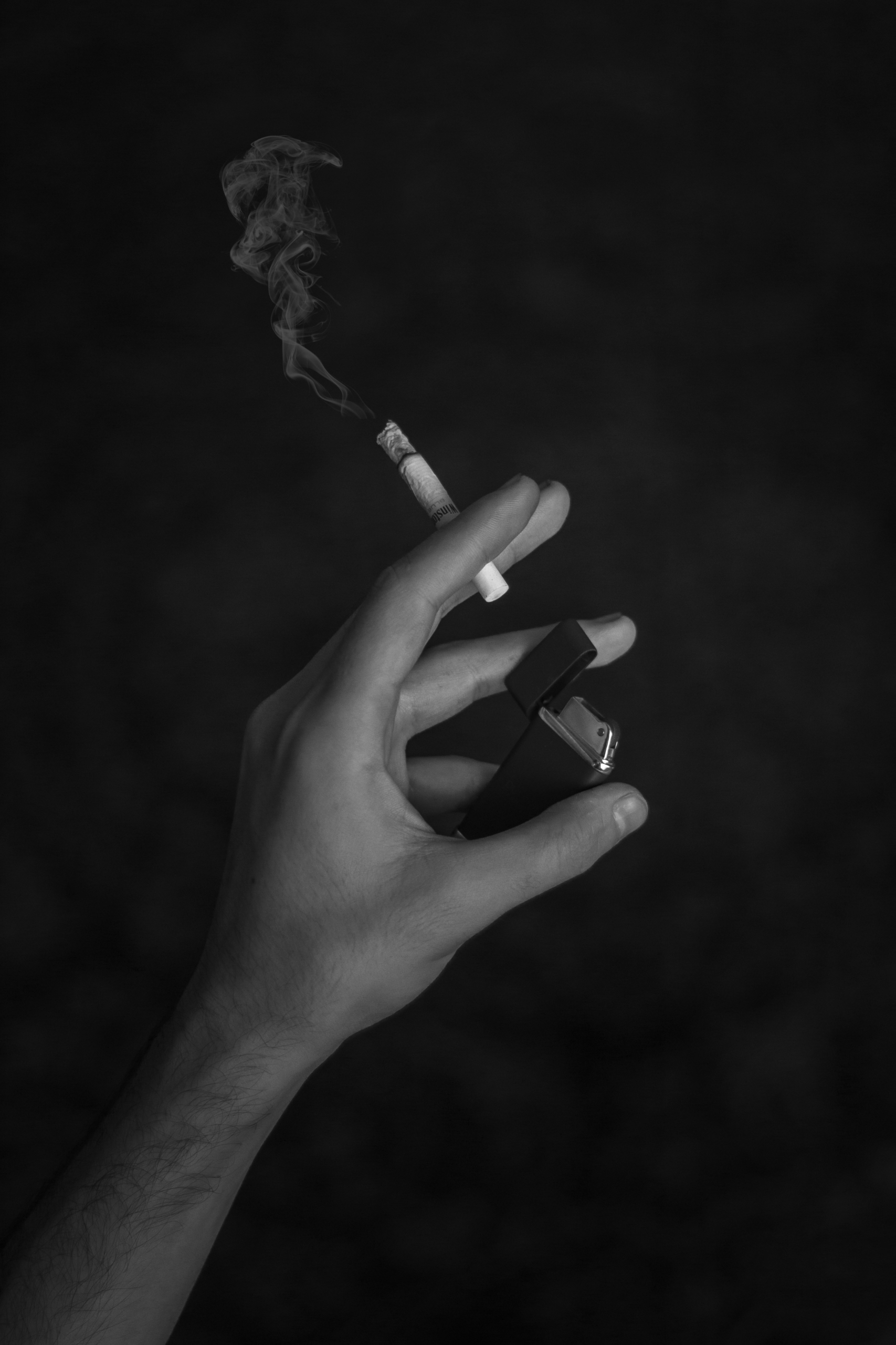 imagine cu background negru cu o mână care ține o țigară
