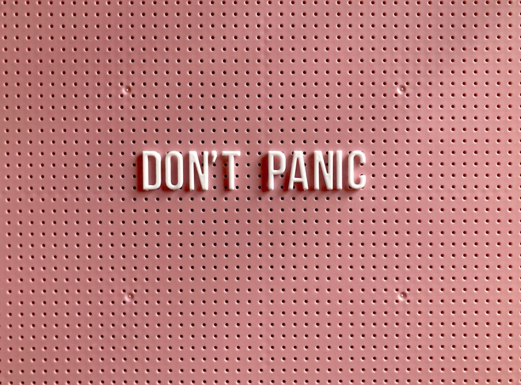 Un semn roz motivational pe care scrie Don’t Panic.