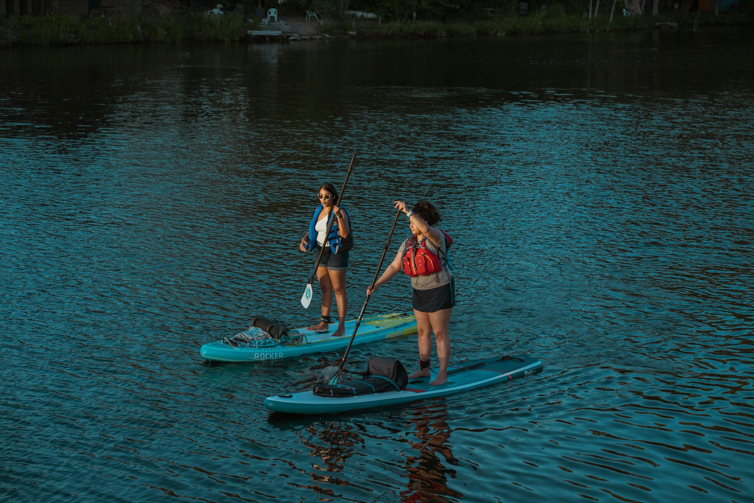 femei care practica paddle boarding pe un lac